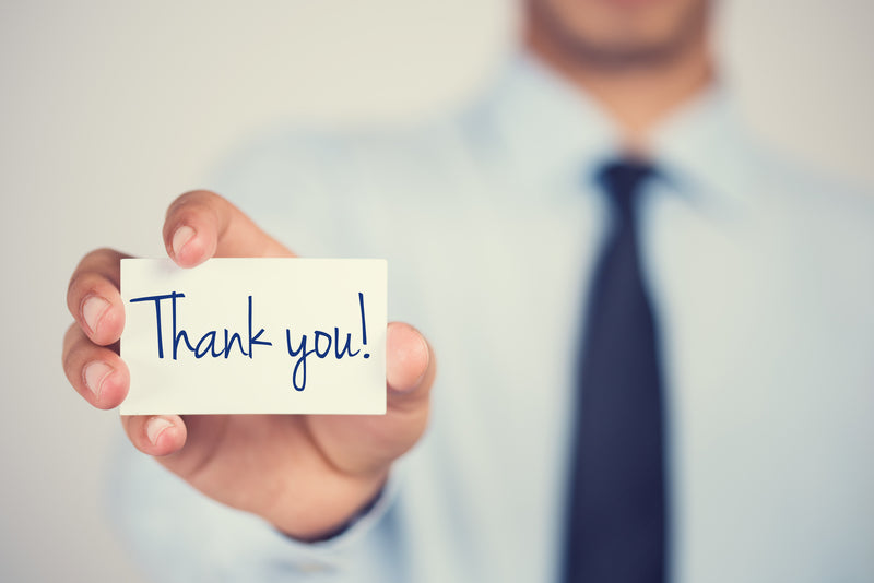 business man holding a card that reads 'thank you'